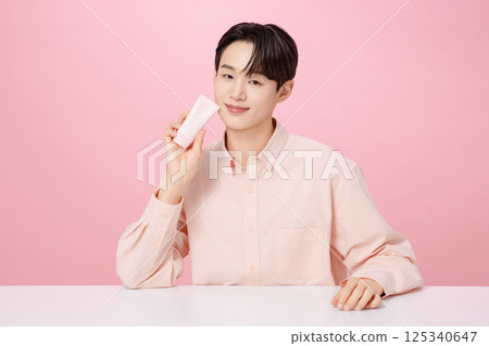 Portrait of a young man posing while holding a tube product 125340647