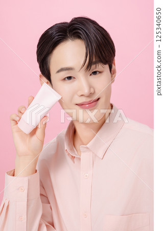Portrait of a young man posing while holding a tube product 125340650