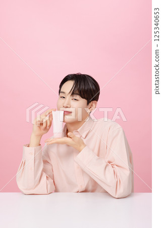 Portrait of a young man posing while holding a tube product 125340653