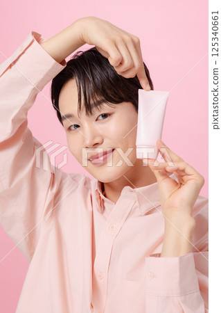 Portrait of a young man posing while holding a tube product Portrait of a young man posing while holding a tube product 125340661