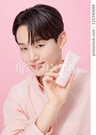 Portrait of a young man posing while holding a tube product 125340666