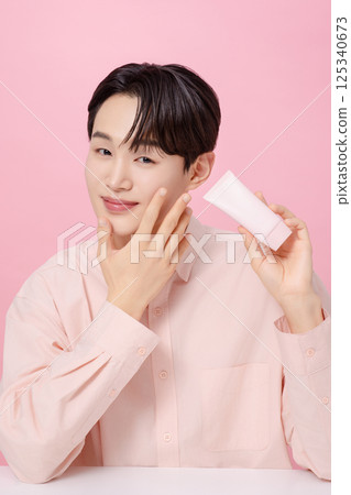 Portrait of a young man posing while holding a tube product 125340673