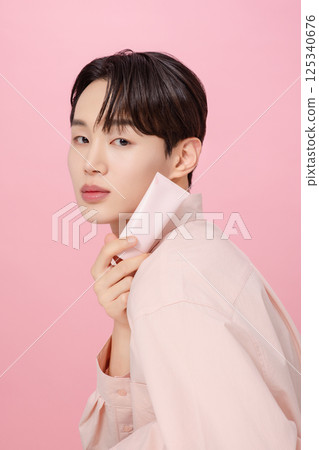 Portrait of a young man posing while holding a tube product 125340676
