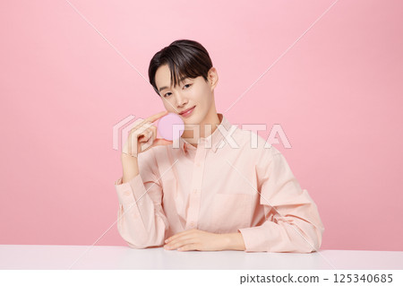 Portrait of a young man posing while holding a cushion Portrait of a young man posing while holding a cushion 125340685