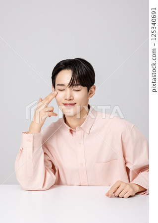 Portrait of a young man smiling while touching his face with his hands Portrait of a young man smiling while touching his face with his hands 125340691