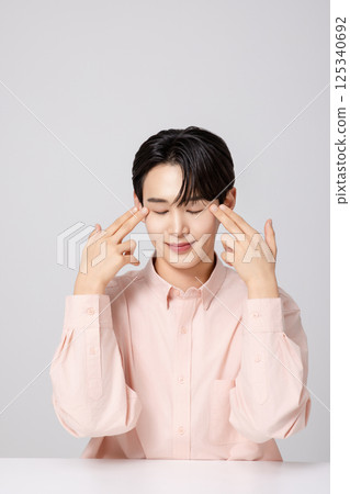 Portrait of a young man smiling while touching his face with his hands Portrait of a young man smiling while touching his face with his hands 125340692