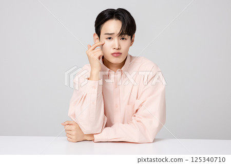 Portrait of a young man smiling while touching his face with his hands Portrait of a young man smiling while touching his face with his hands 125340710