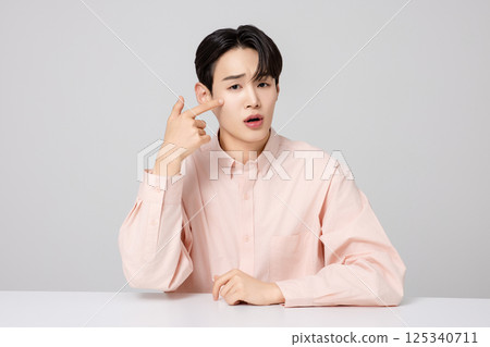 Portrait of a young man smiling while touching his face with his hands Portrait of a young man smiling while touching his face with his hands 125340711