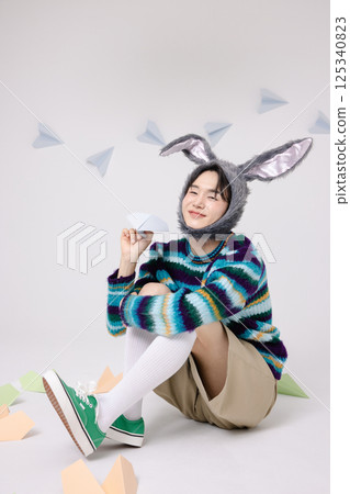 Cropped view of young man wearing bunny hat sitting surrounded by paper airplanes 125340823