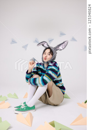 Cropped view of young man wearing bunny hat sitting surrounded by paper airplanes 125340824