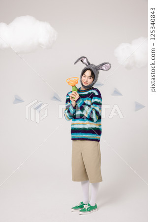 Portrait of a man standing wearing a rabbit hat and holding soap bubbles 125340843