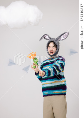 Portrait of a man standing wearing a rabbit hat and holding soap bubbles Portrait of a man standing wearing a rabbit hat and holding soap bubbles 125340847