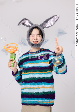Portrait of a man standing wearing a rabbit hat and holding soap bubbles Portrait of a man standing wearing a rabbit hat and holding soap bubbles 125340851