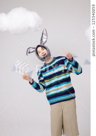 A man wearing a rabbit hat and playing with soap bubbles 125340859