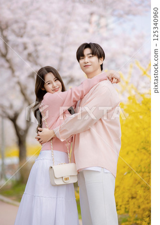 A friendly couple enjoying a date on a street filled with cherry blossoms 125340960