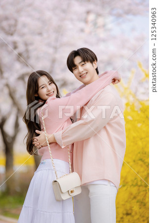 A friendly couple enjoying a date on a street filled with cherry blossoms 125340963