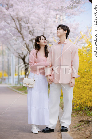 Portrait of a young man photographing cherry blossoms with a camera 125340966