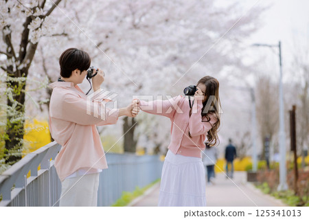 A friendly couple enjoying a date on a street filled with cherry blossoms A friendly couple enjoying a date on a street filled with cherry blossoms 125341013