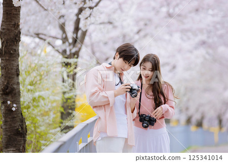 A friendly couple enjoying a date on a street filled with cherry blossoms A friendly couple enjoying a date on a street filled with cherry blossoms 125341014