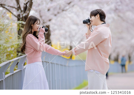 A friendly couple enjoying a date on a street filled with cherry blossoms A friendly couple enjoying a date on a street filled with cherry blossoms 125341016