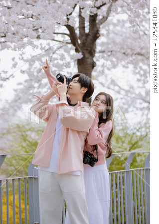A friendly couple enjoying a date on a street filled with cherry blossoms A friendly couple enjoying a date on a street filled with cherry blossoms 125341030