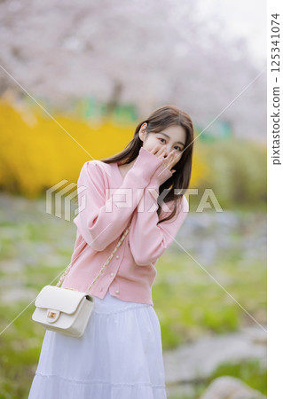 A lovely woman taking the photo of her life with spring flowers in the background 125341074