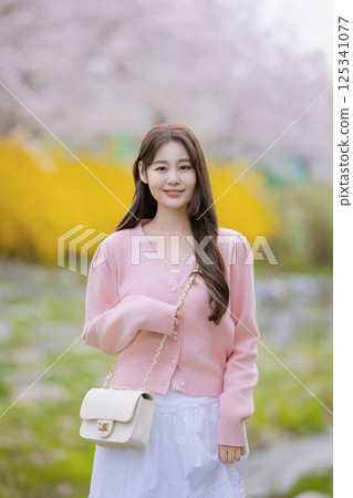A lovely woman taking the photo of her life with spring flowers in the background 125341077