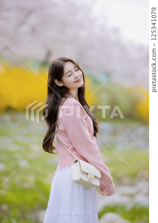 A lovely woman taking the photo of her life with spring flowers in the background 125341079