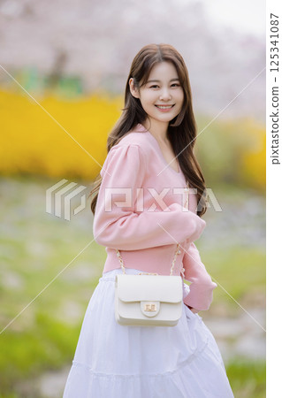 A lovely woman taking the photo of her life with spring flowers in the background 125341087
