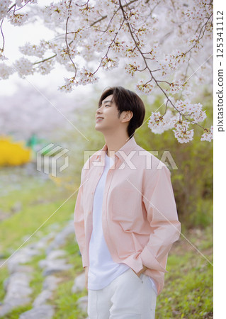 A handsome man taking a photo with cherry blossoms in the background 125341112