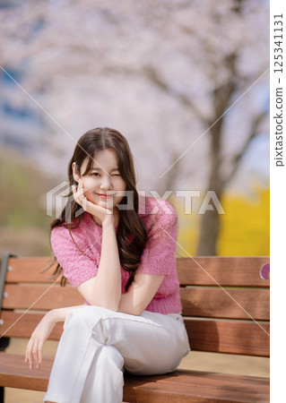 A lovely woman in her 20s sitting on a bench 125341131