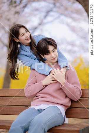 A couple enjoying a date on a park bench with flowers in full bloom 125341176