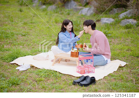A couple enjoying a date while having a picnic in the park A couple enjoying a date while having a picnic in the park 125341187