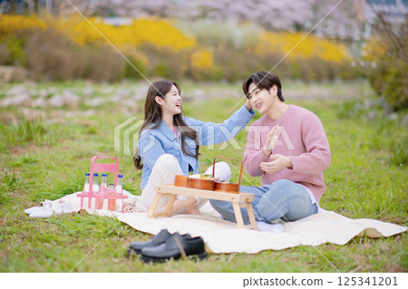 A couple enjoying a date while having a picnic in the park A couple enjoying a date while having a picnic in the park 125341201