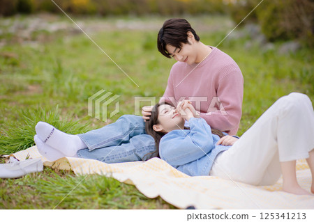 A couple enjoying a date while having a picnic in the park A couple enjoying a date while having a picnic in the park 125341213