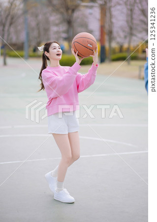 A young couple enjoying a basketball date in the park 125341236