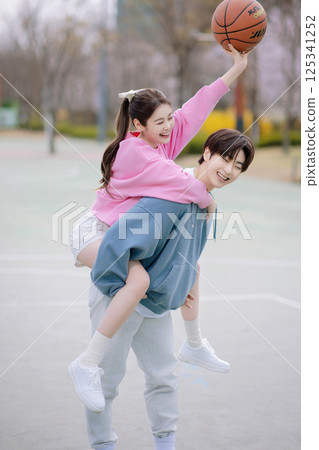 A young couple enjoying a basketball date in the park 125341252