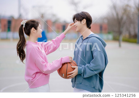 A young couple enjoying a basketball date in the park 125341256
