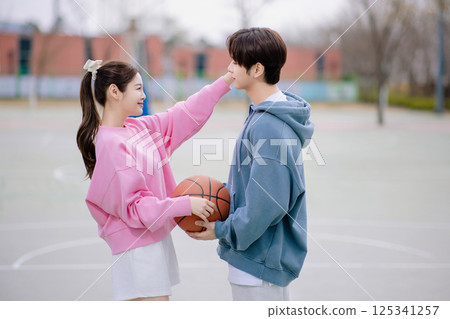 A young couple enjoying a basketball date in the park 125341257
