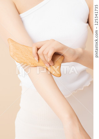 A woman massaging her arms with gua sha 125341735