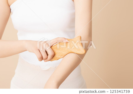 A woman massaging her arms with gua sha 125341739