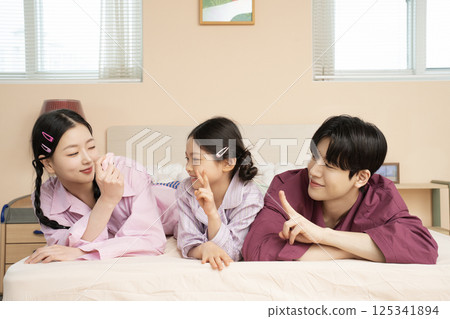 A family of three sitting affectionately together on the living room sofa 125341894