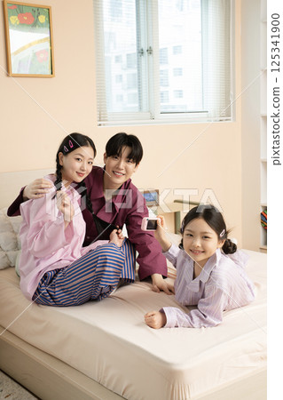 A family of three sitting affectionately together on the living room sofa 125341900