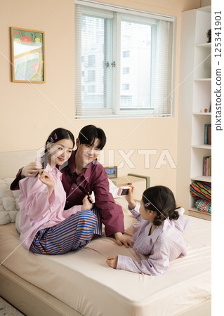 A family of three sitting affectionately together on the living room sofa 125341901