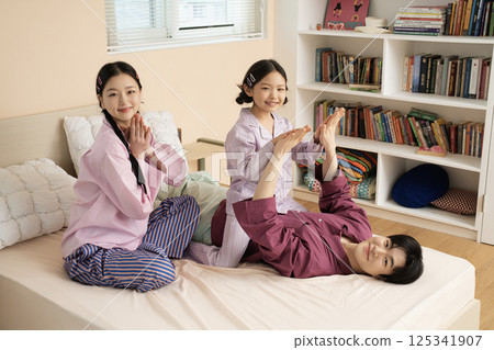 A family of three sitting affectionately together on the living room sofa 125341907