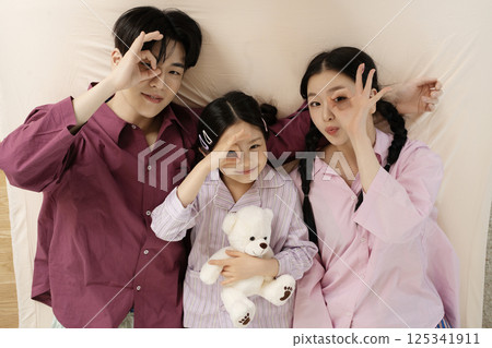 A family of three sitting affectionately together on the living room sofa 125341911