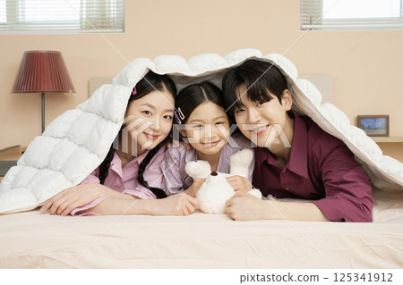 A family of three sitting affectionately together on the living room sofa A family of three sitting affectionately together on the living room sofa 125341912