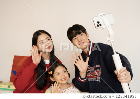 A family looking at an iPad while unpacking their suitcase 125341953
