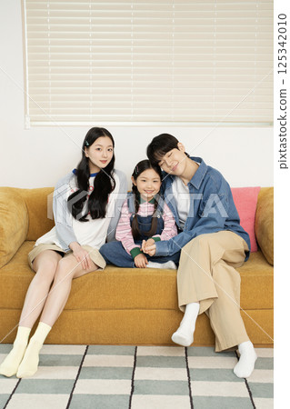 A young couple lovingly looking at their daughter lying on the floor A young couple lovingly looking at their daughter lying on the floor 125342010