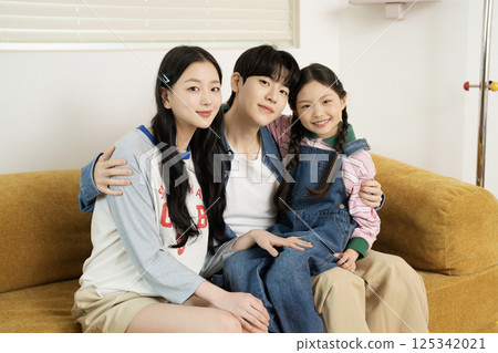 Daughter building domino blocks with her mother and father lying on the sofa 125342021
